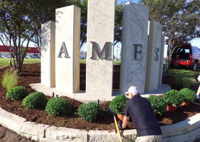 Ames Signage on 13th street - volunteer helps clean up landscaping