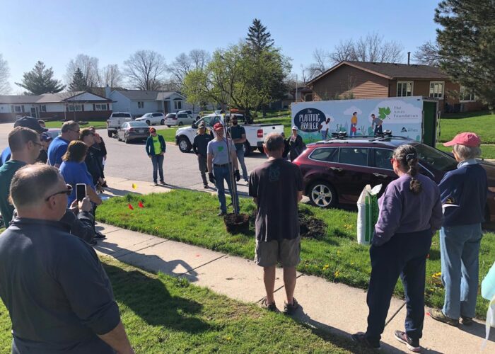 group of people standing around a tree at the tree planting event